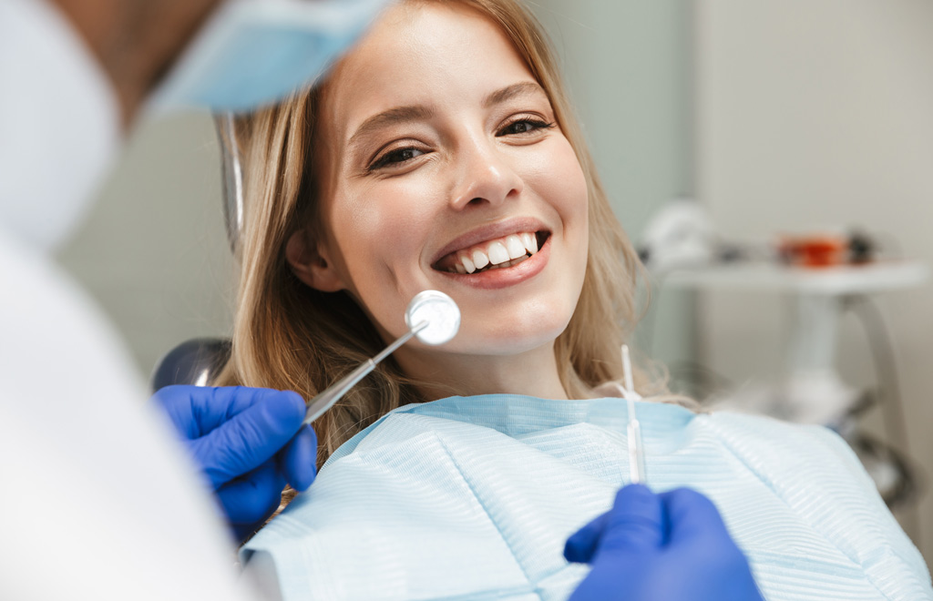 Image of satisfied woman sitting in dental chair while professio